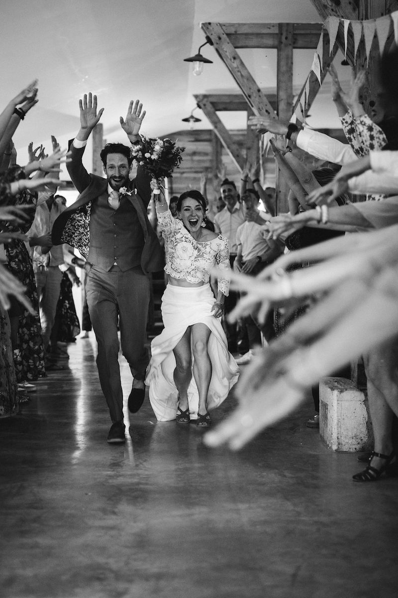 Black and white photo of joyful wedding celebration with dancing and raised hands.