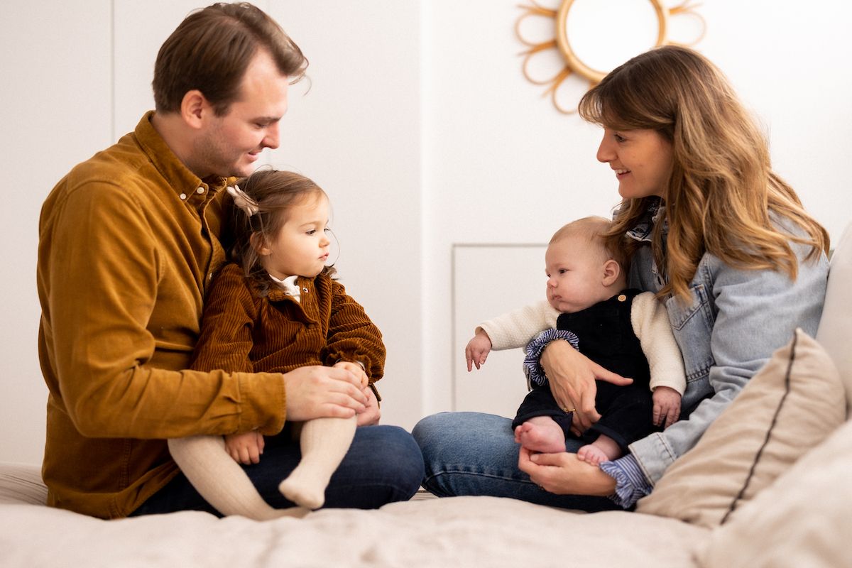 A family sitting together on a couch in coordinated brown and denim outfits.