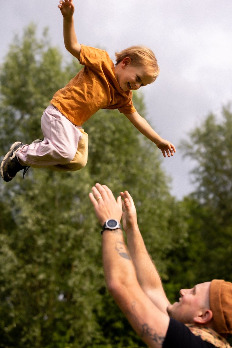 Action sequence of someone tossing a child in the air during outdoor playtime.