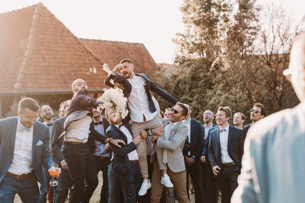 Joyous celebration with group jumping and cheering outdoors at sunset.