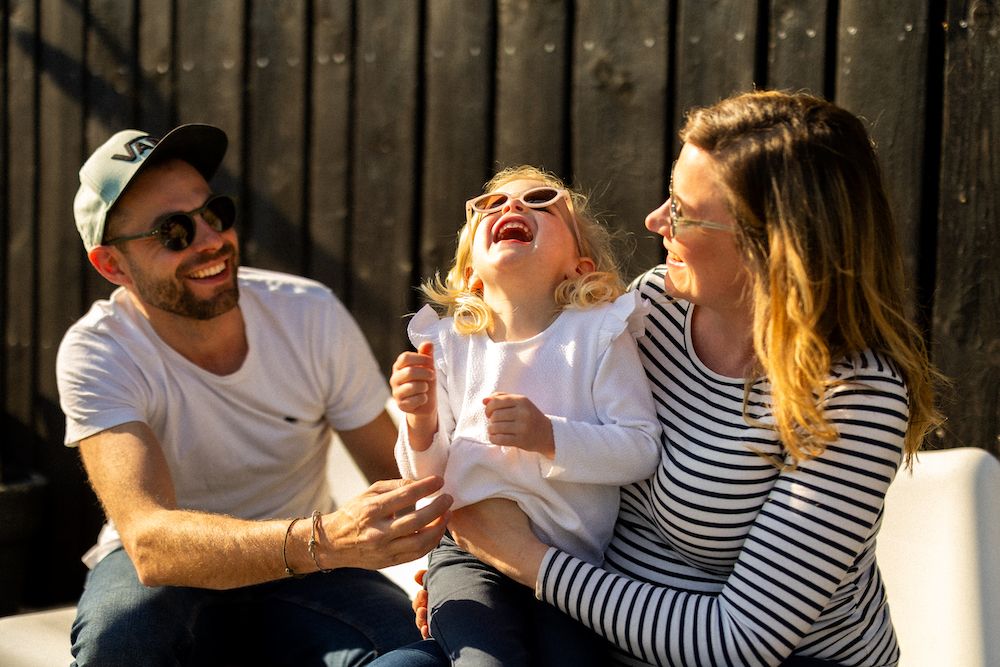 Candid laughter shared on outdoor bench during golden hour.