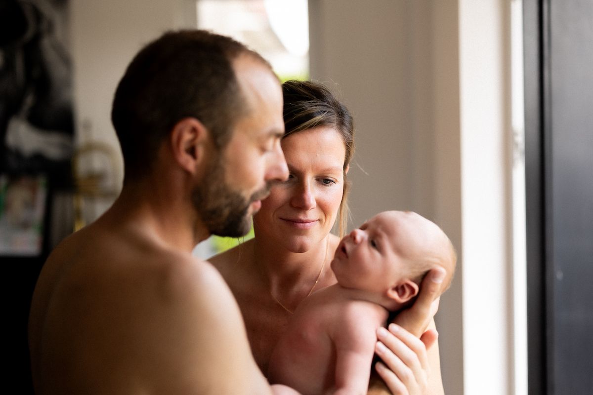 Intimate family moment by window with newborn baby.