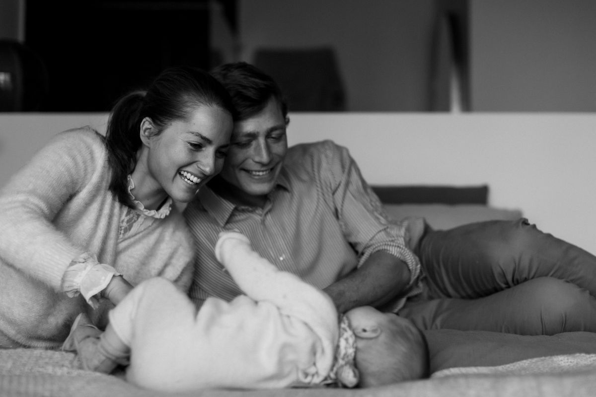An intimate monochrome family moment captured on a bed.