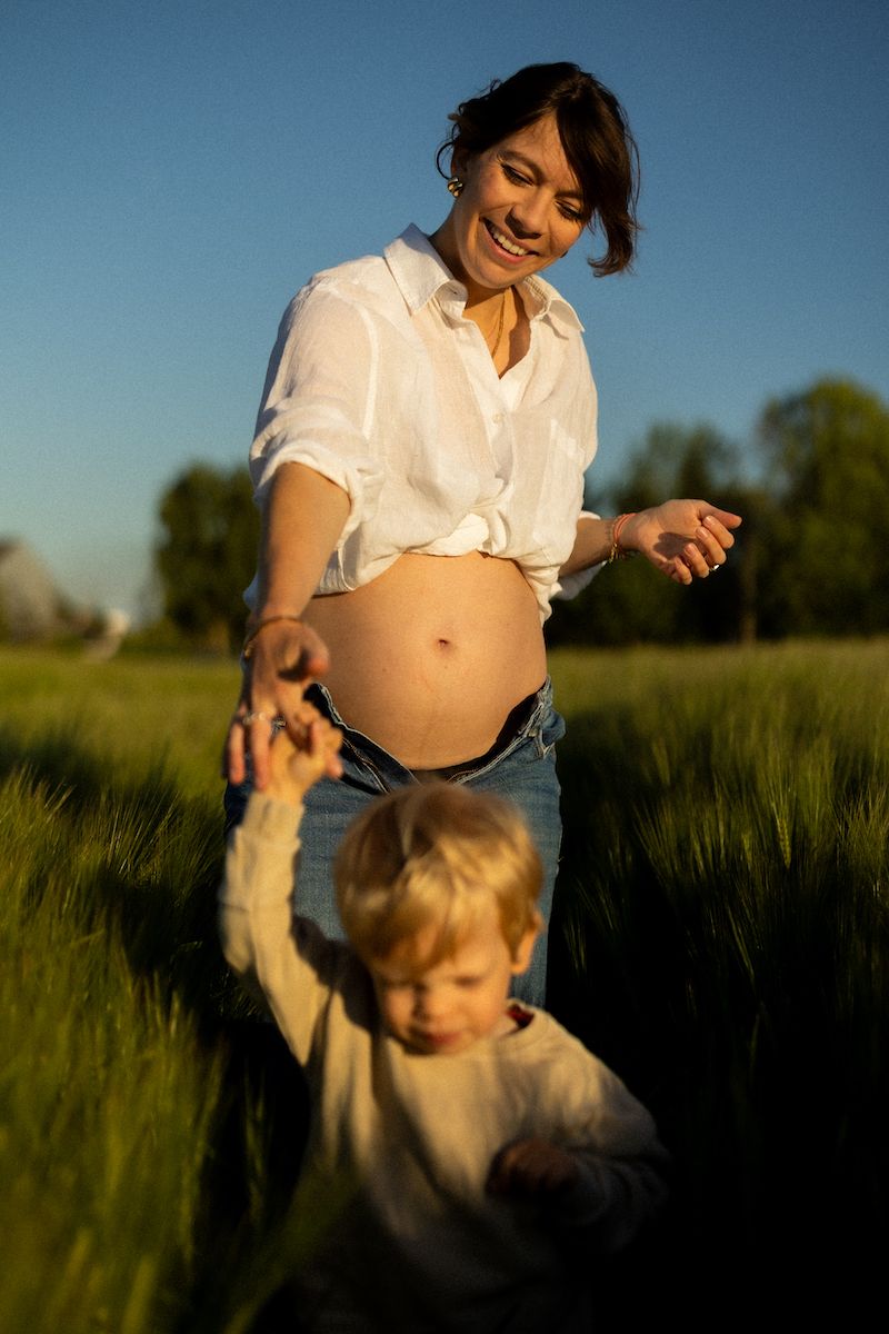 Family playing together in a sunlit grassy field during golden hour.