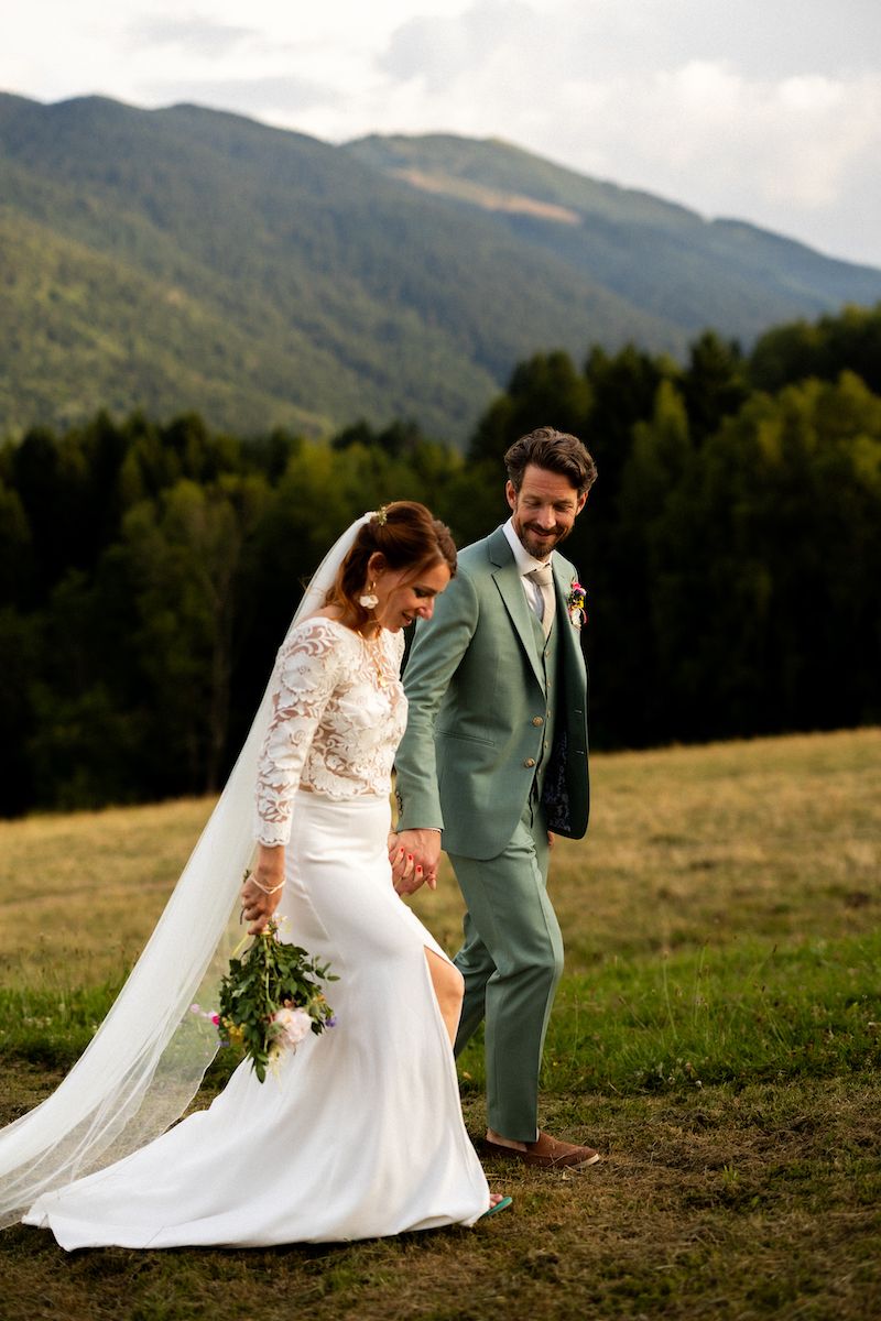 A wedding couple walking and posing in a mountain meadow with flowing white dress.