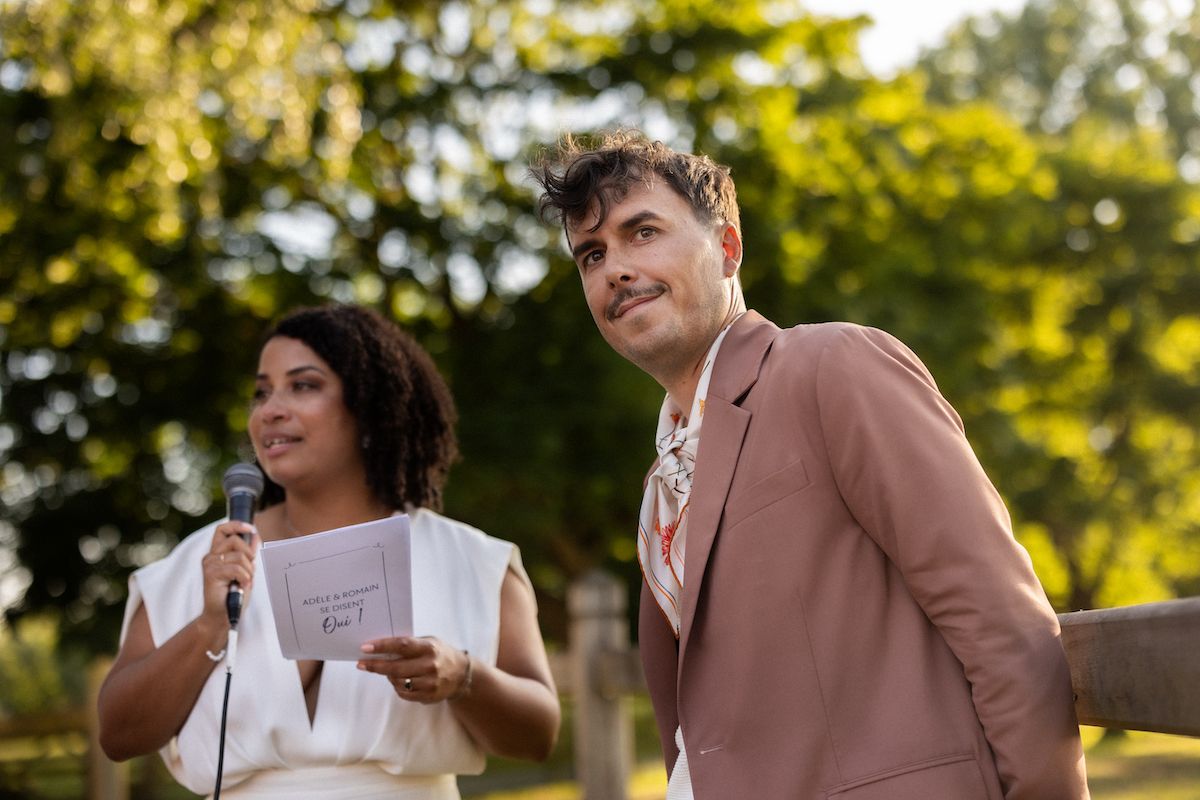 Wedding attendees share laughter and joyful moments outdoors in formal attire.