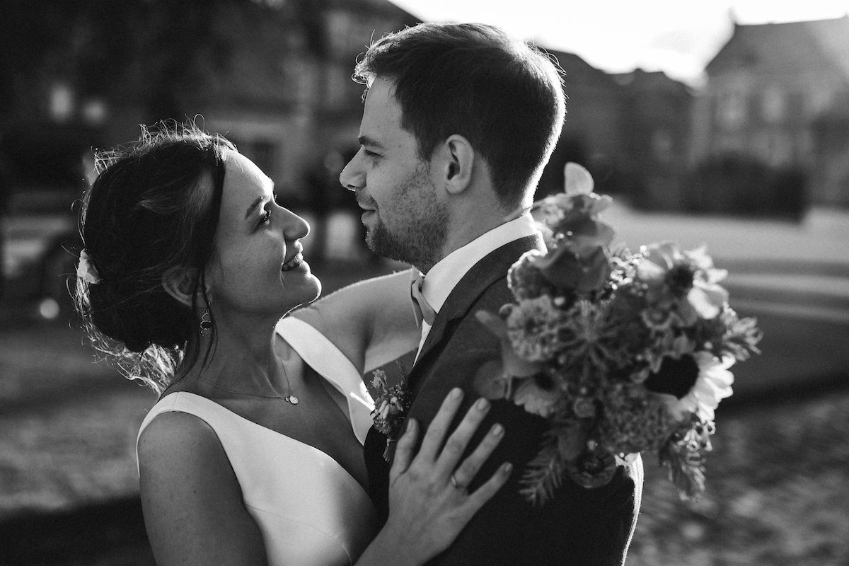 A black and white portrait of newlyweds sharing an intimate moment with floral bouquet.