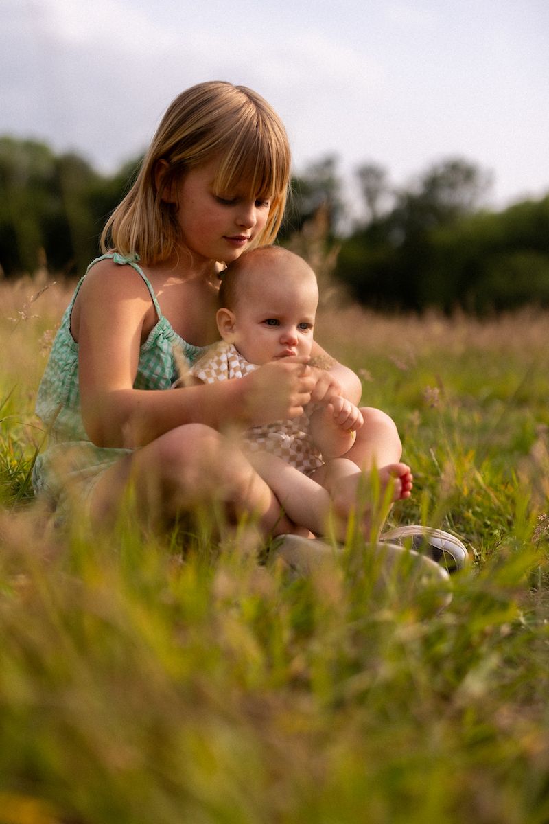 Close-up shot of gentle nurturing moment in golden wildflower field at sunset.