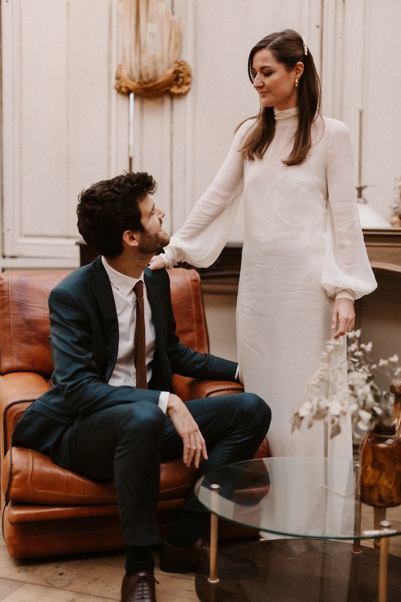 An intimate scene with a couple in formal wear sharing a tender moment on a leather couch.
