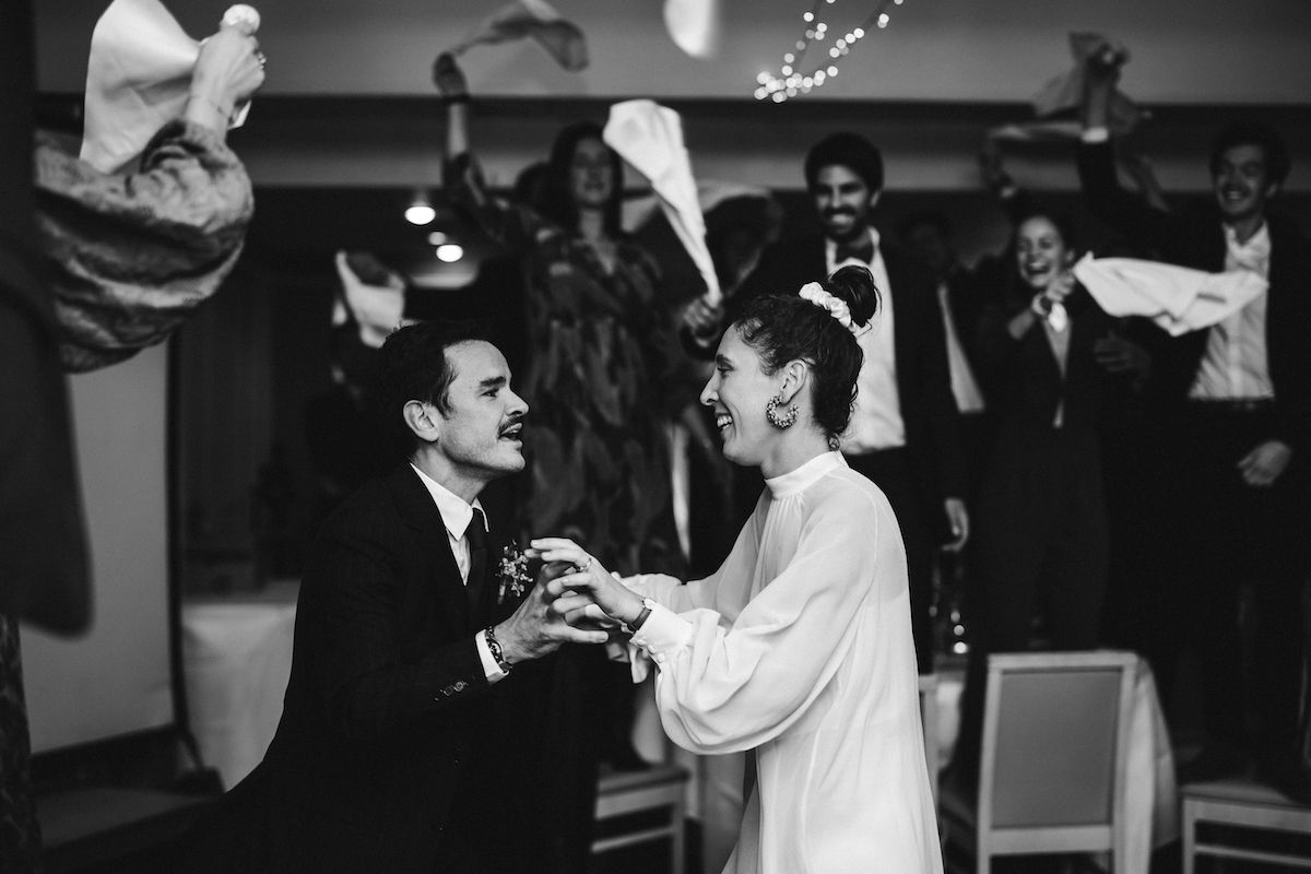 A black and white photo captures a joyful celebration at a wedding reception.