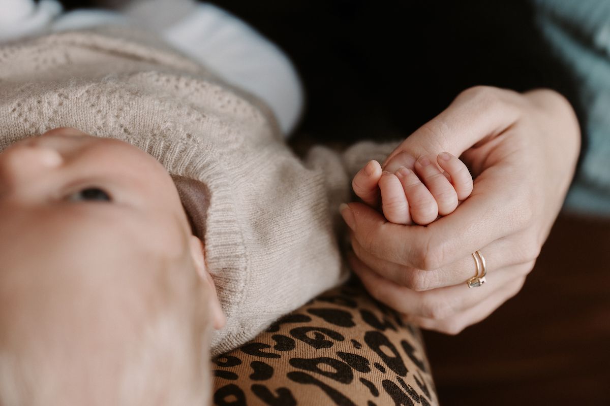 Intimate close-up shot showing gentle hands and soft fabric textures.