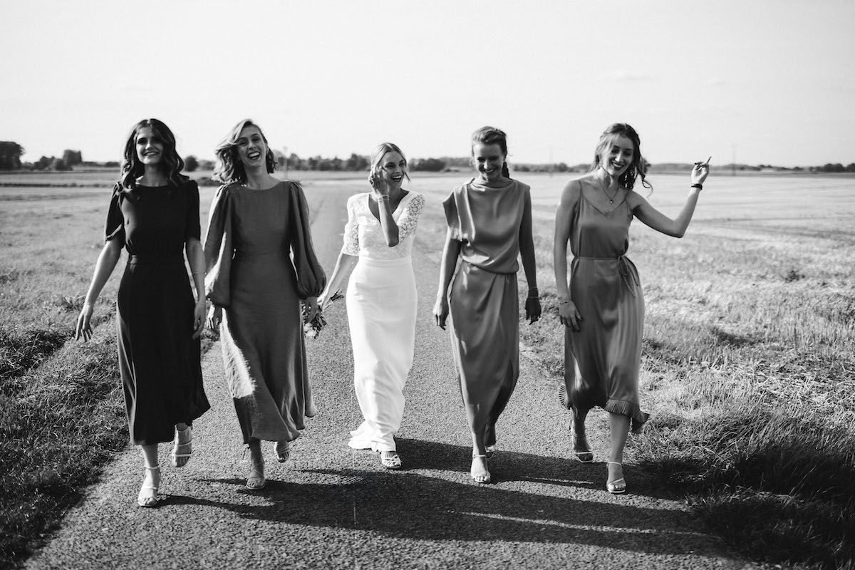 Wedding party walking together across open field in black and white.