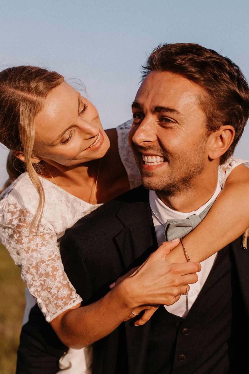 A joyful candid moment between a couple laughing together in warm sunlight.