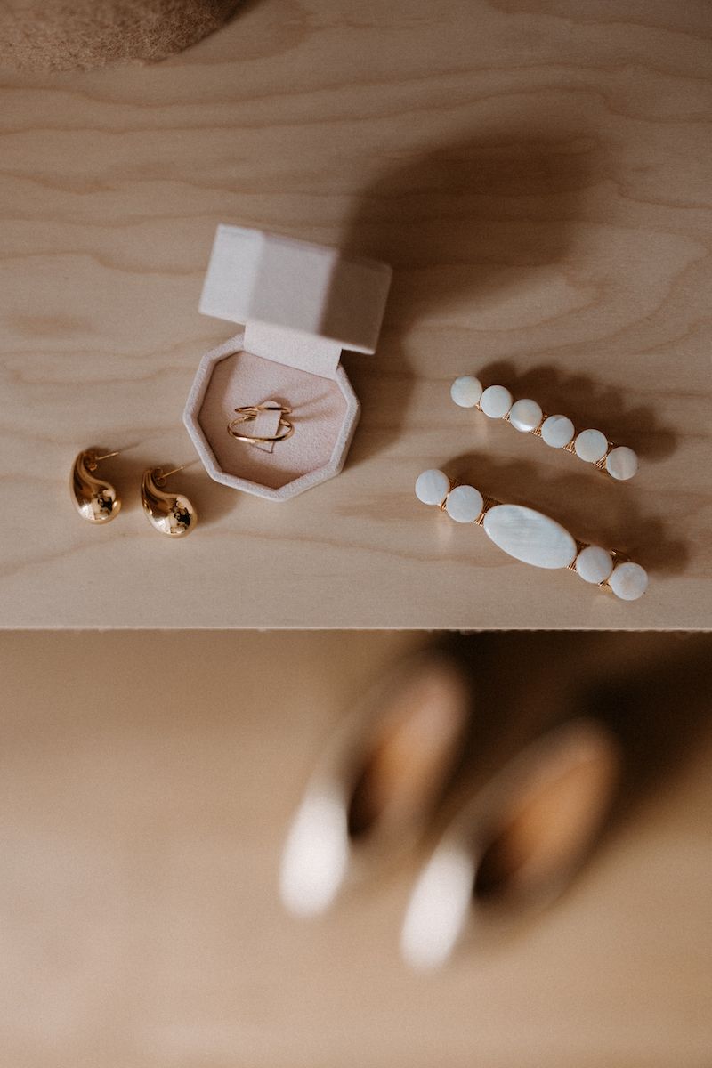 White beaded wedding accessories and jewelry arranged on a light wooden surface.