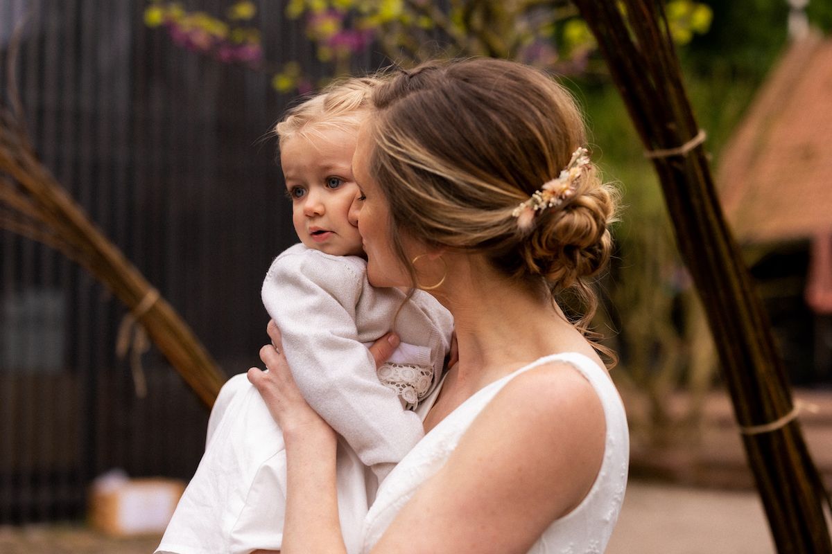 A tender moment between mother and child at an outdoor wedding celebration.