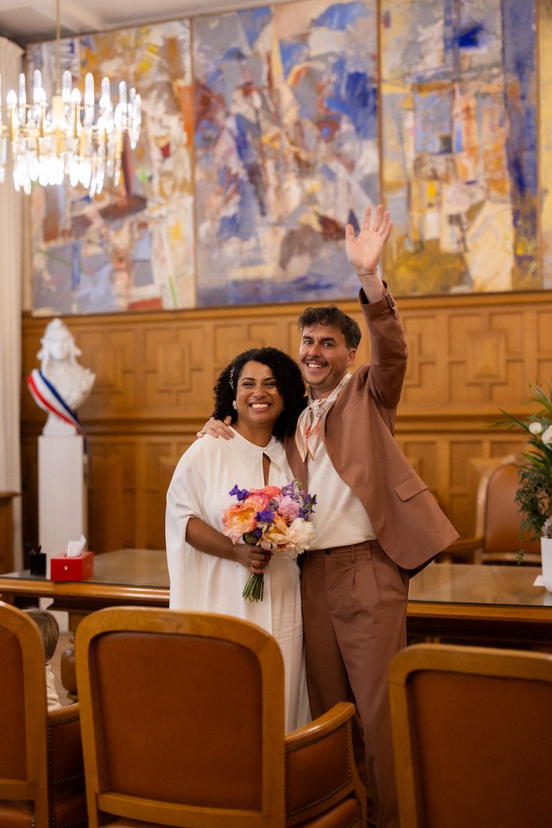 A happy couple celebrates in a church with beautiful wall murals and a chandelier overhead.