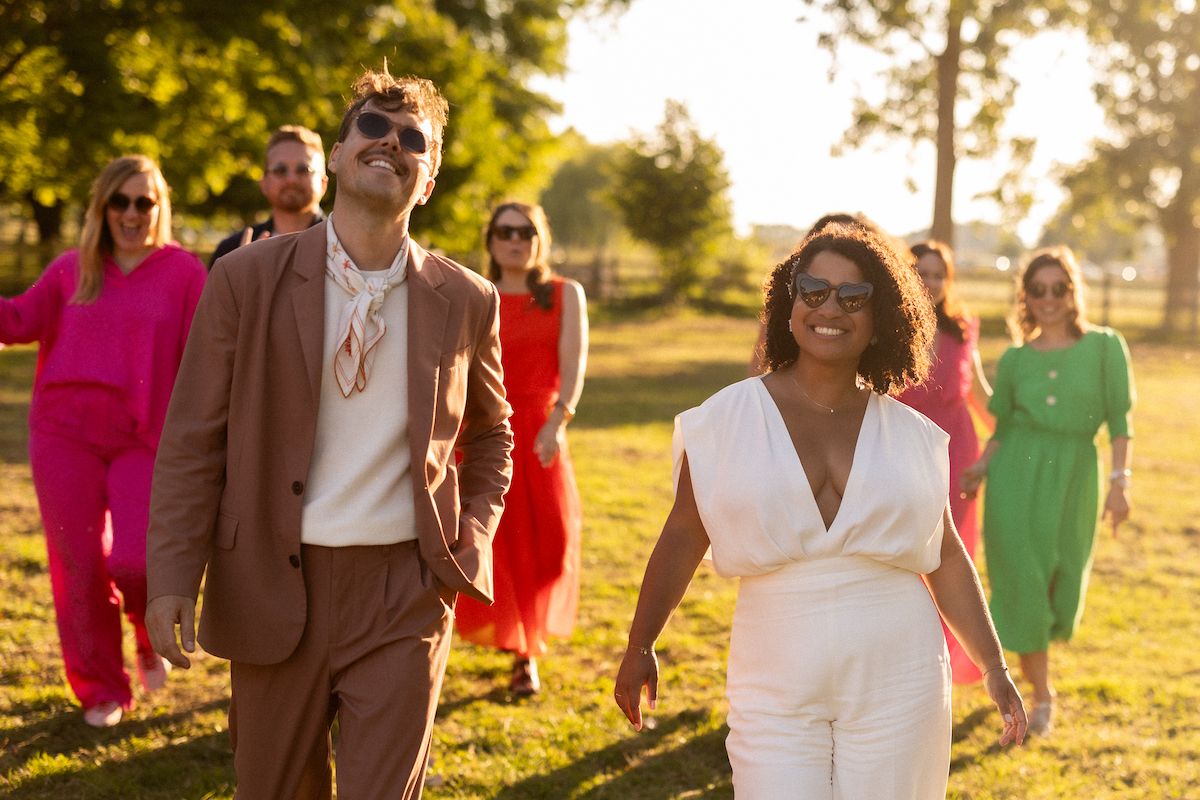 Wedding party walks together in vibrant outfits during golden hour outdoor photography session.
