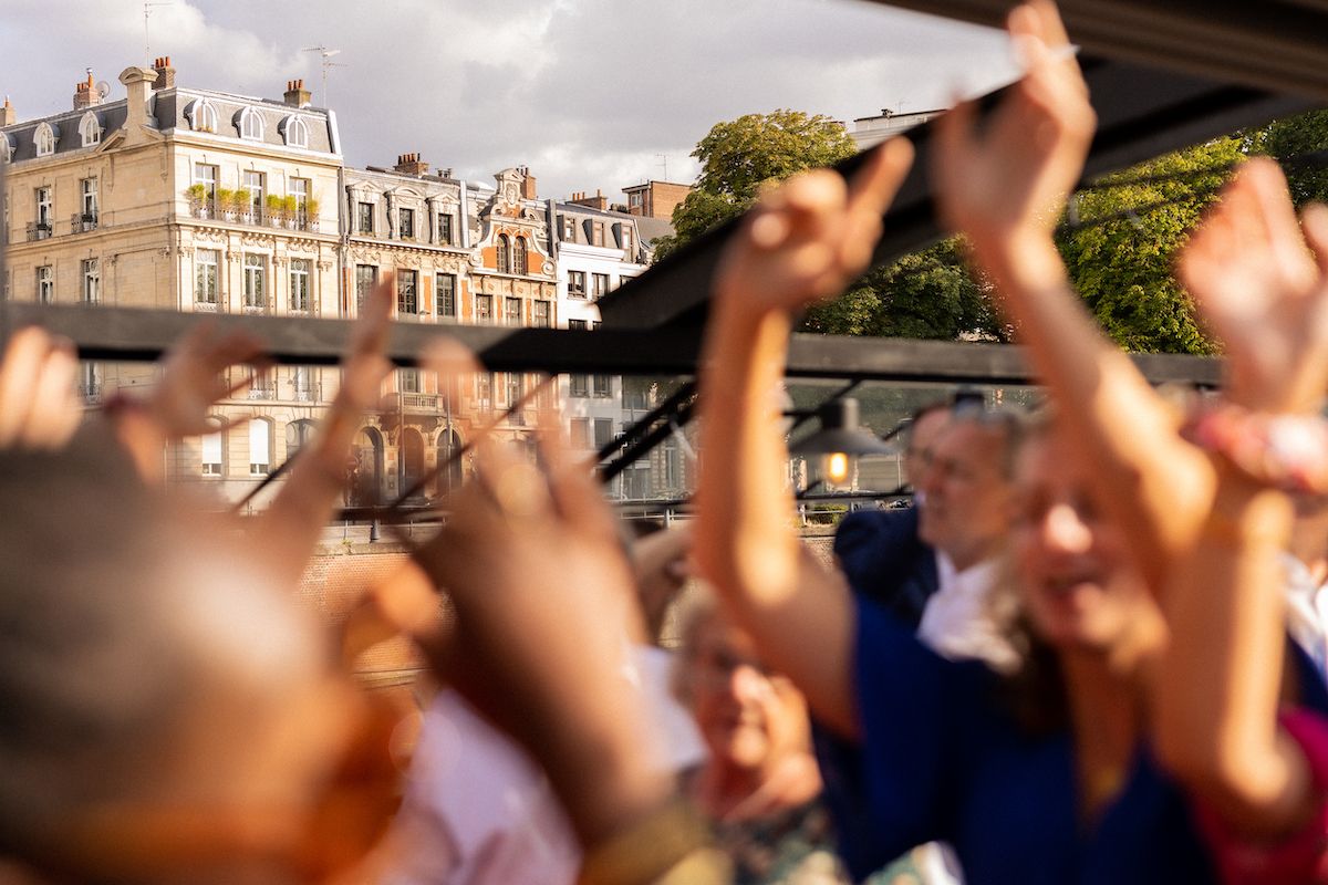 Crowd with raised hands celebrating against backdrop of classic European architecture.