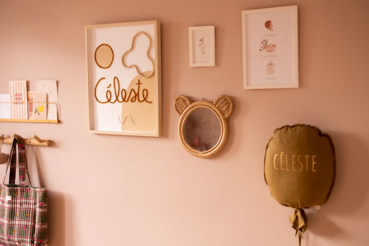 Nursery wall decor featuring a bear-shaped mirror and artwork in soft pink tones.