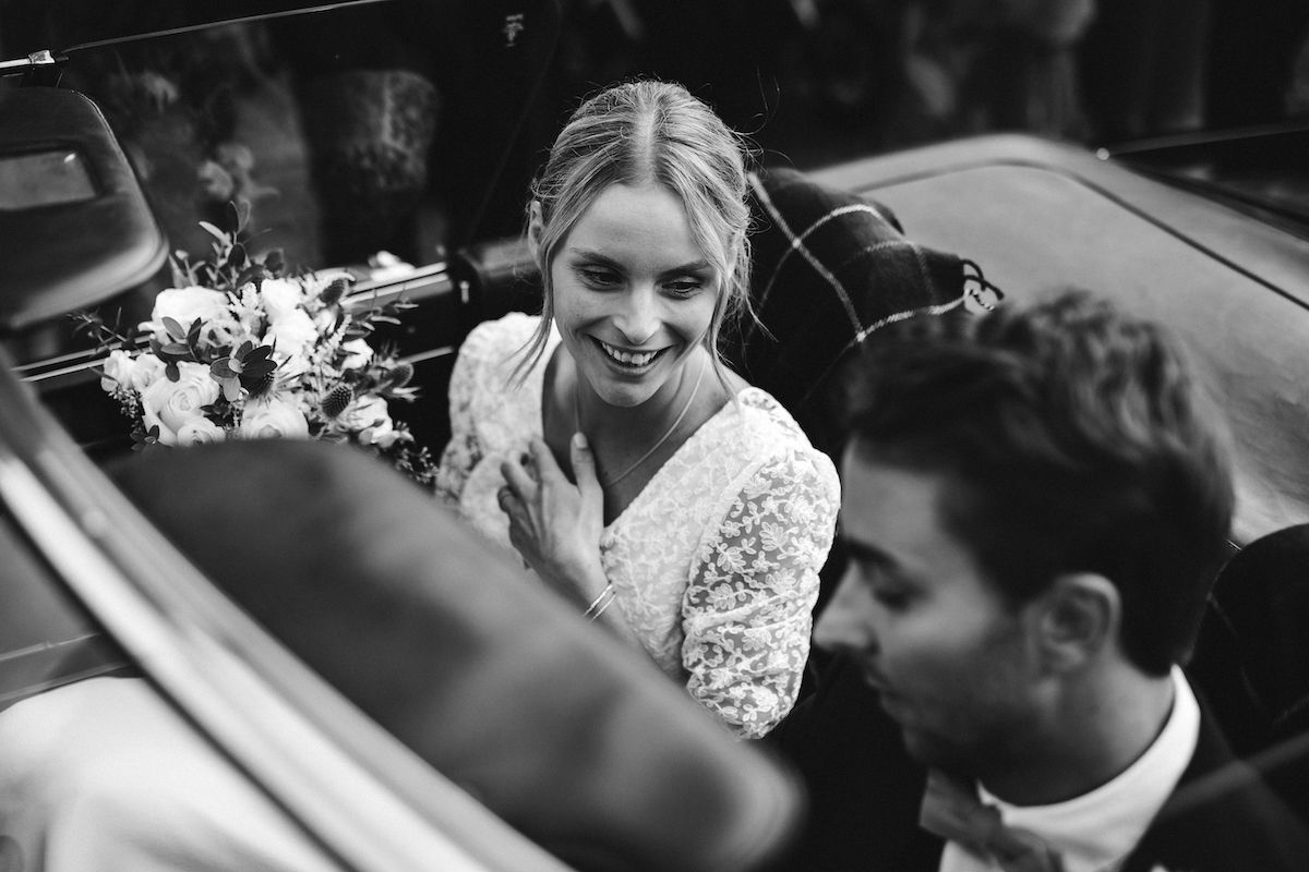 Classic black and white wedding portrait in vintage car with florals.