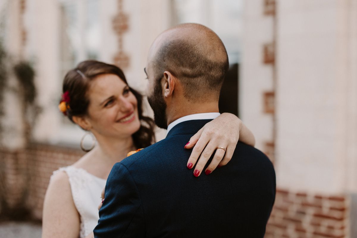 A tender moment captured between newlyweds against brick architecture.