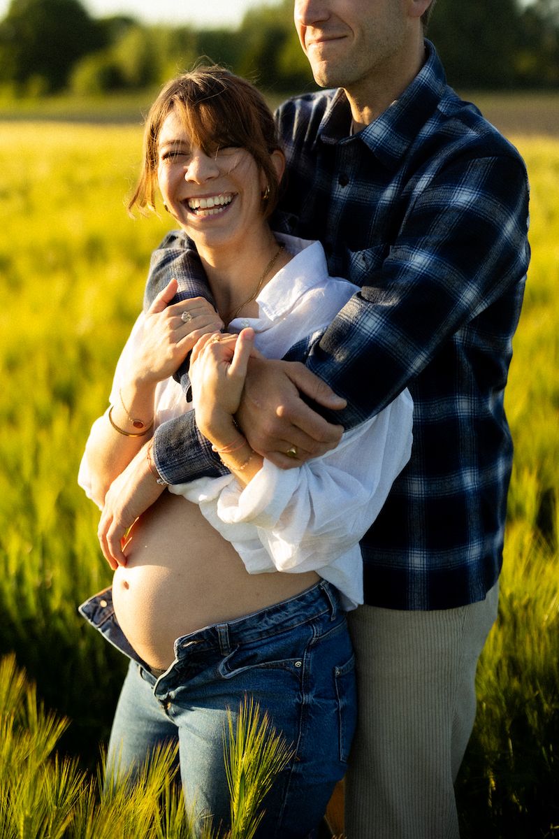 Intimate family moment captured in vibrant wheat field at sunset.
