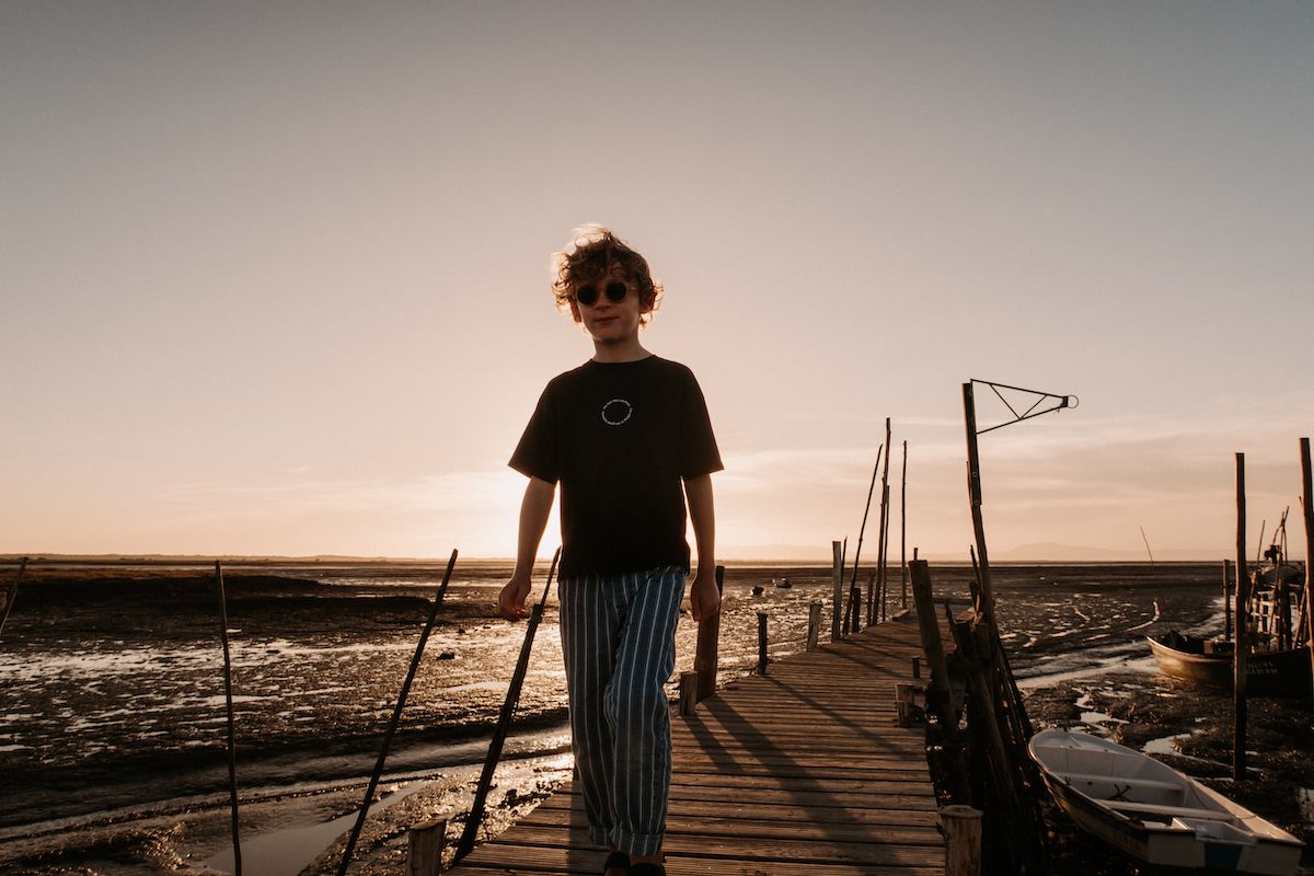 Silhouette of a person walking on a wooden pier at sunset.