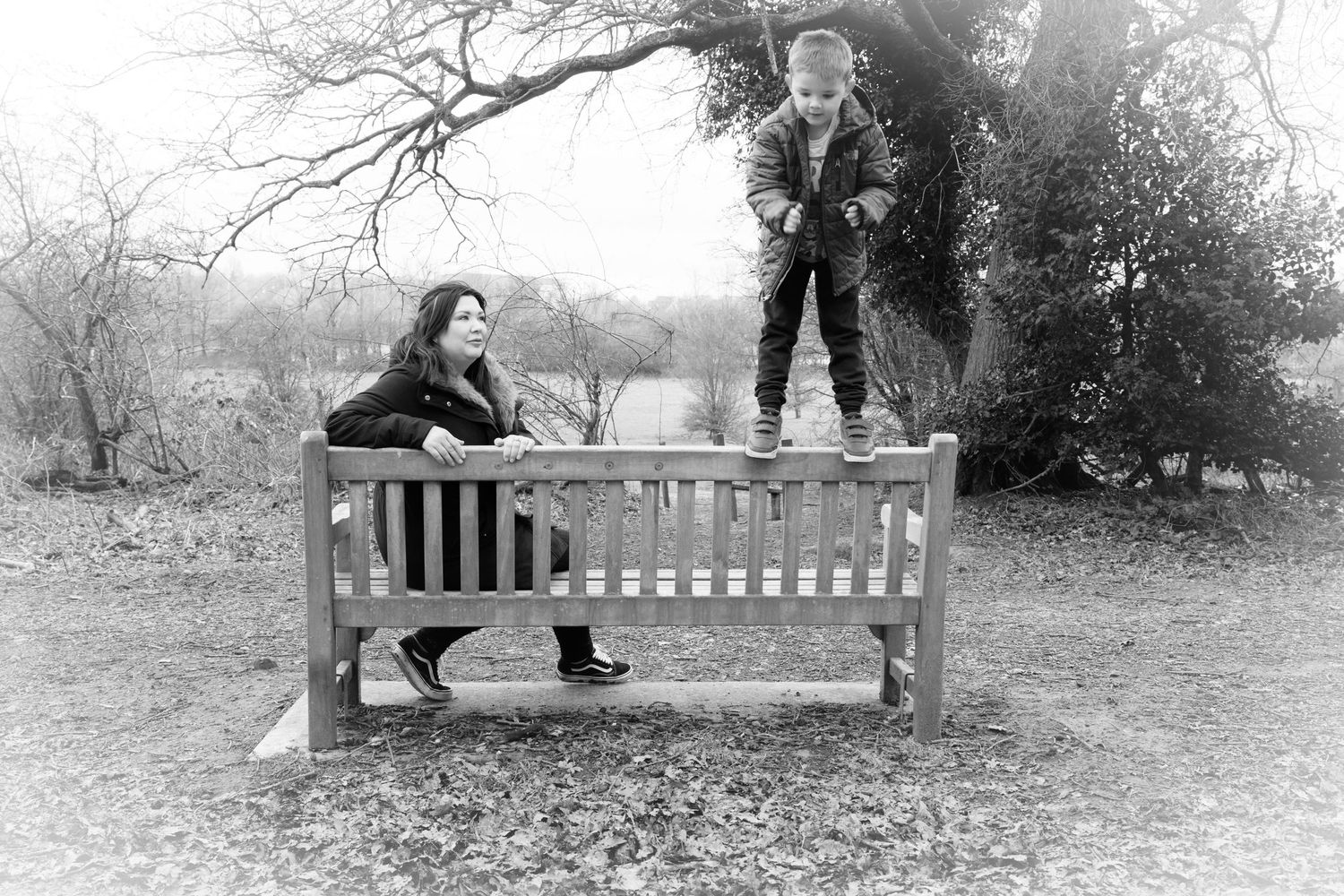 Black and white scene of playful interactions around a park bench in winter.