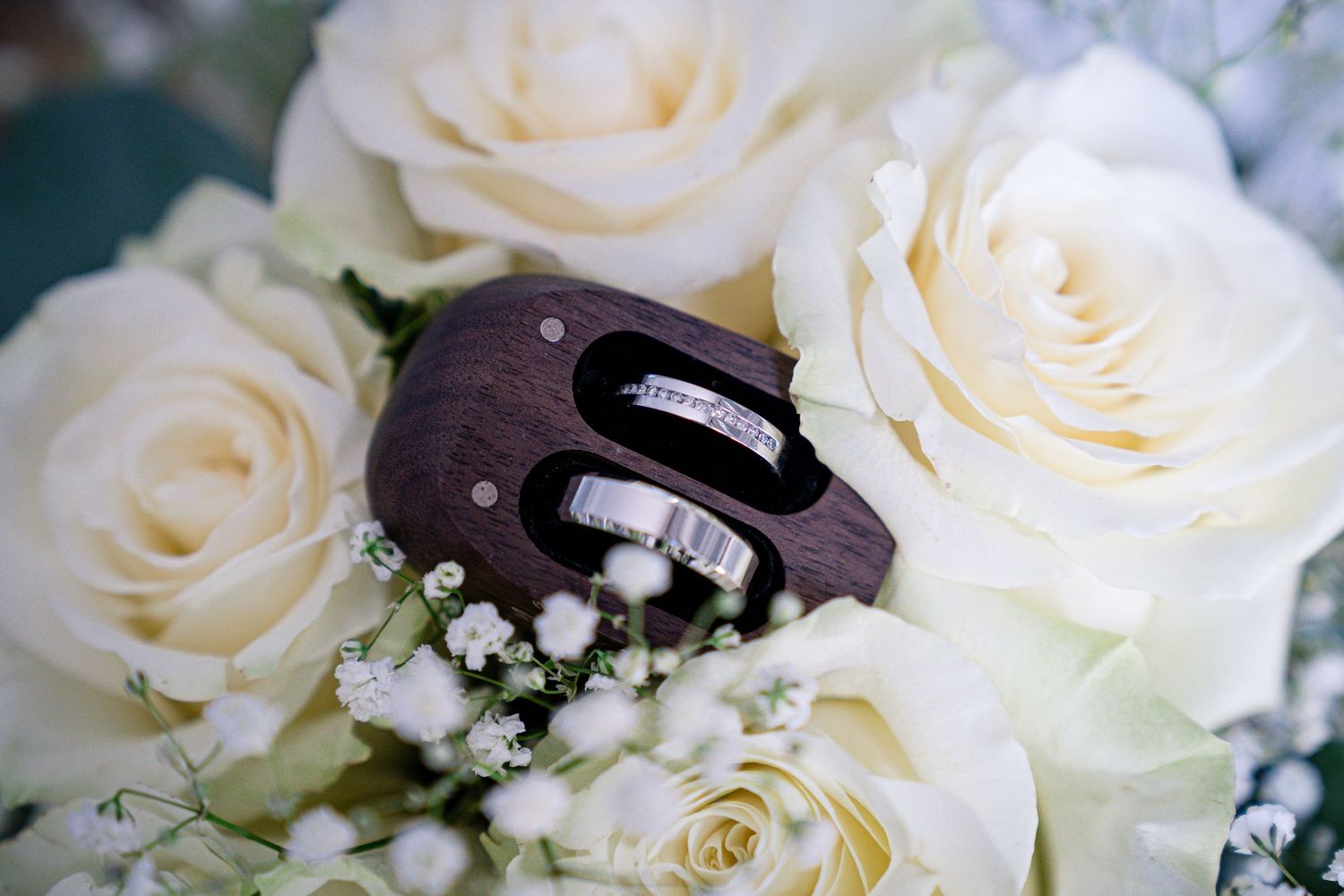 Wedding rings nestled among white roses and baby's breath flowers.