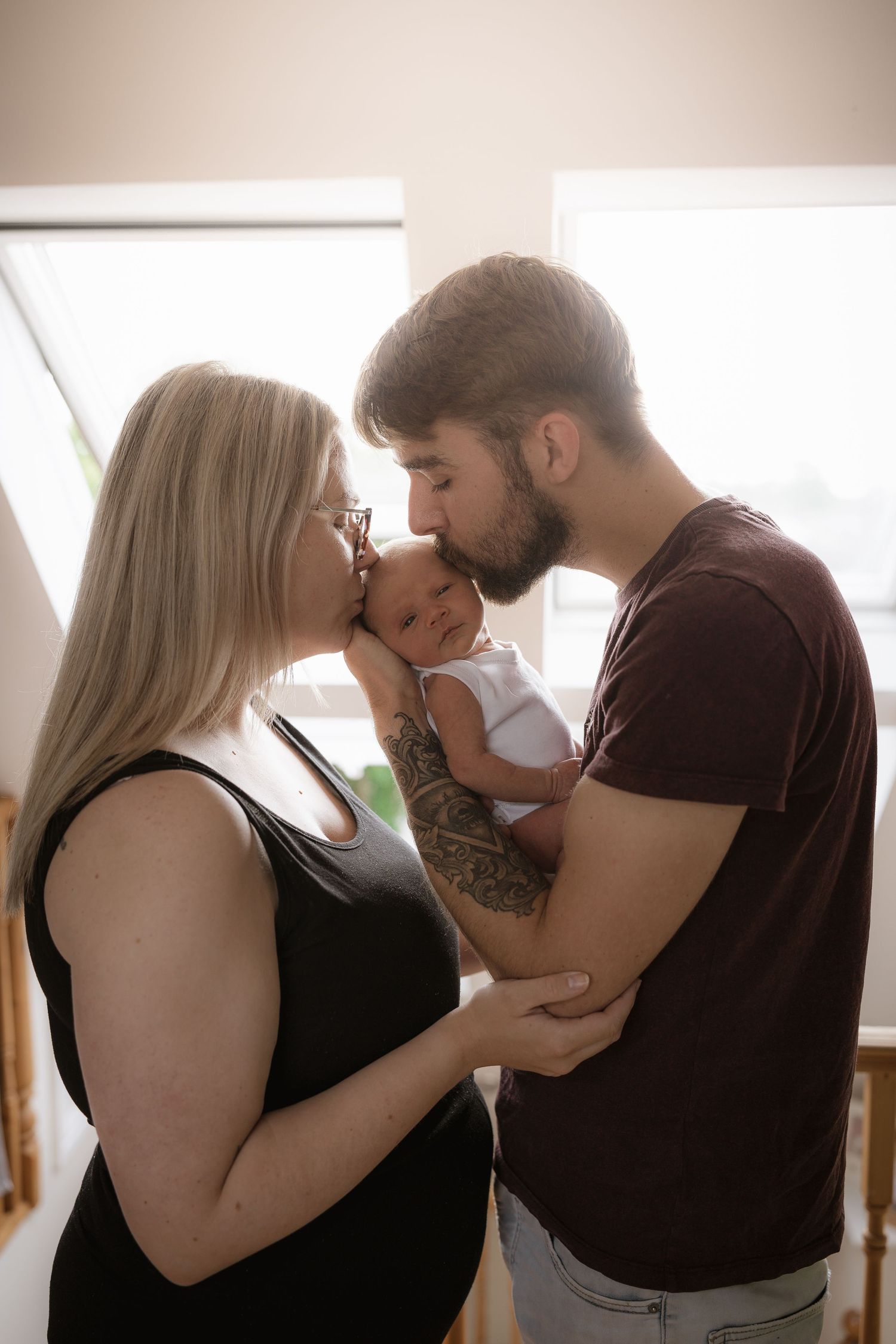 A tender family moment with a newborn baby being held between two caregivers.