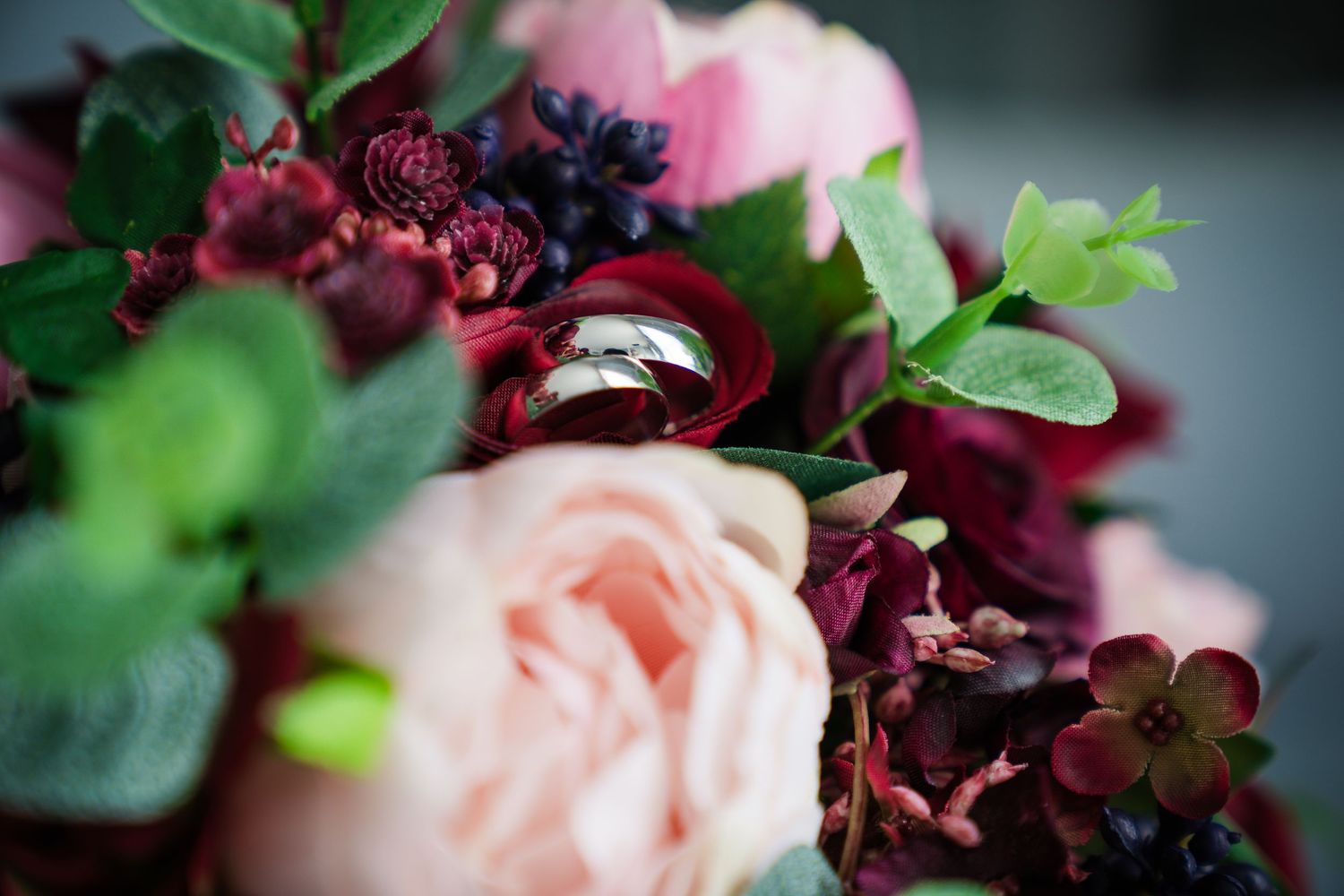 Delicate pink roses and deep burgundy floral arrangements create an elegant wedding backdrop.