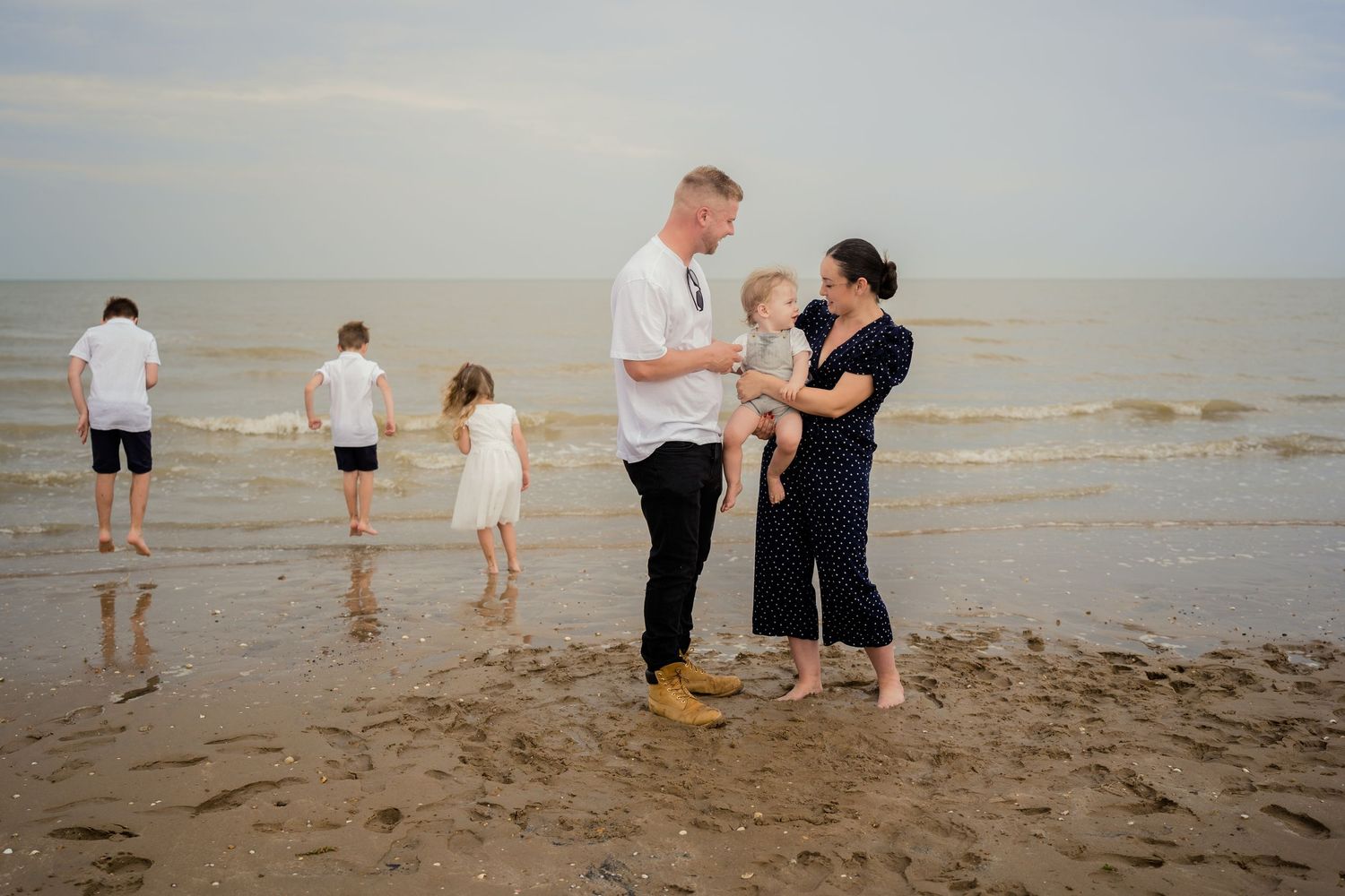 Family enjoying leisure time together on sandy beach near water.