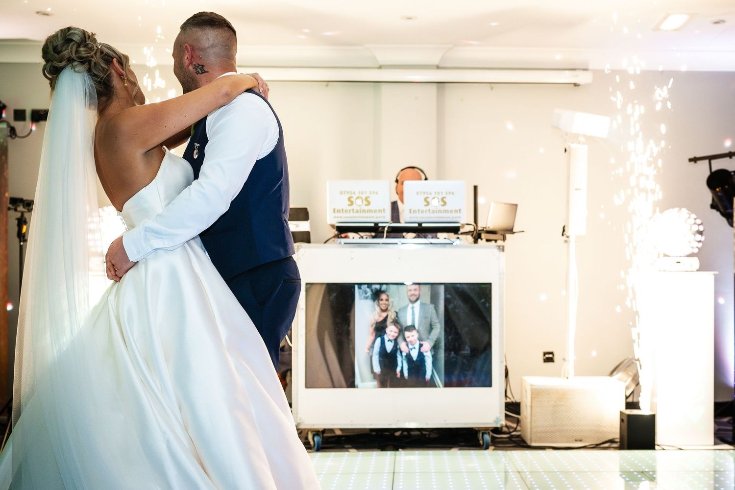 Newlyweds share their first dance in a reception hall with sparkling lights.