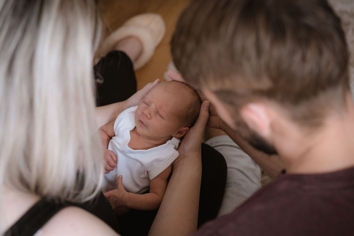 A peaceful sleeping newborn being cradled by caregivers in soft lighting.