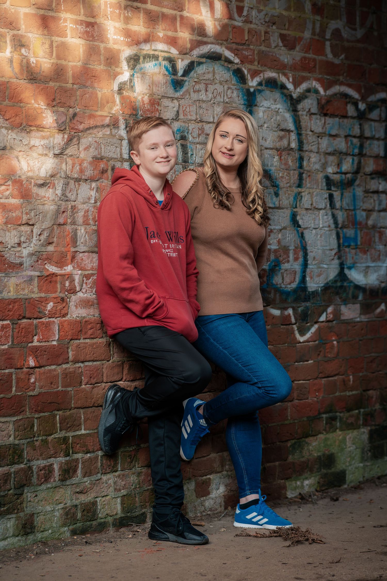 Family portrait session against a graffitied brick wall outdoors.