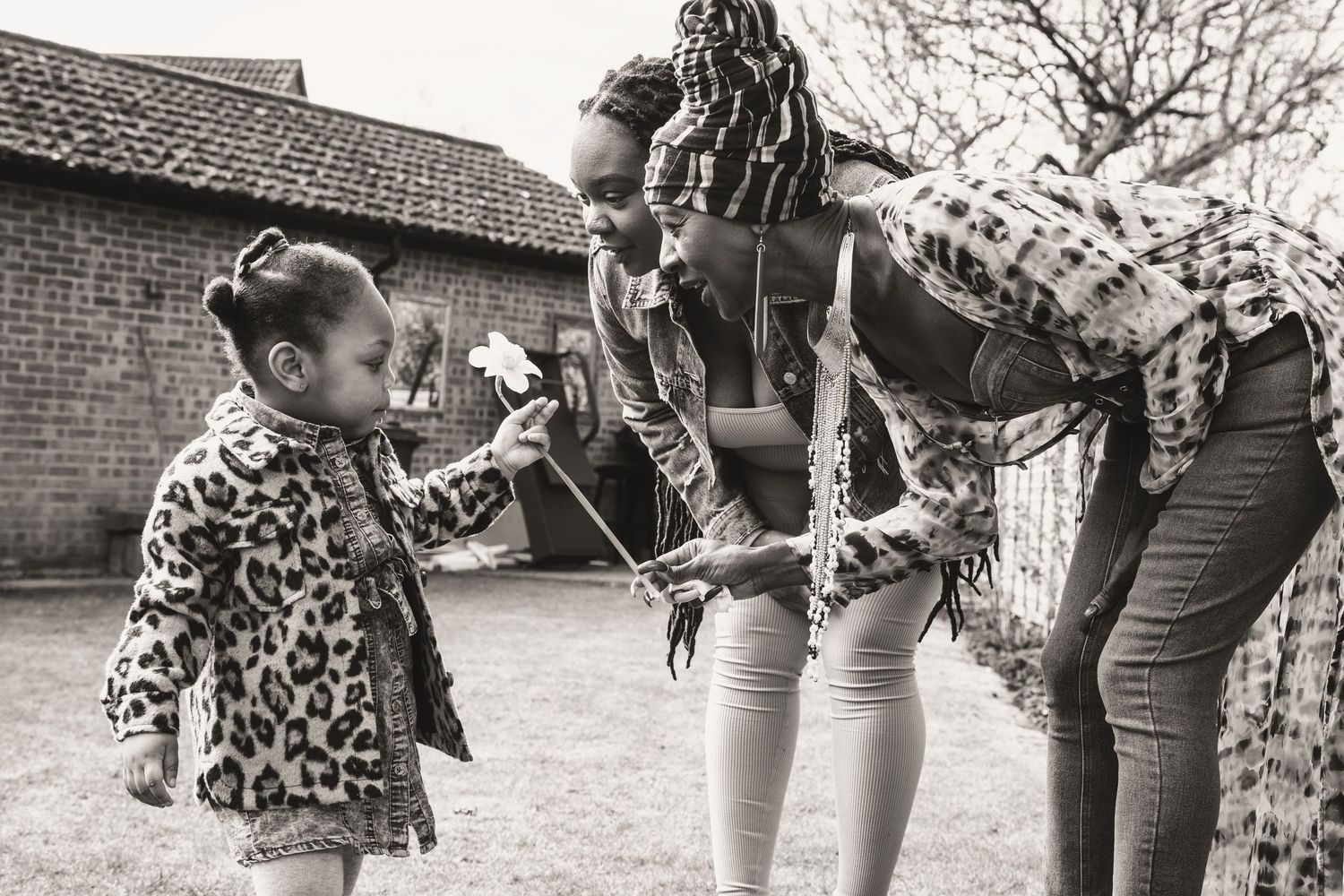 Black and white photo of people interacting outdoors near a brick building.