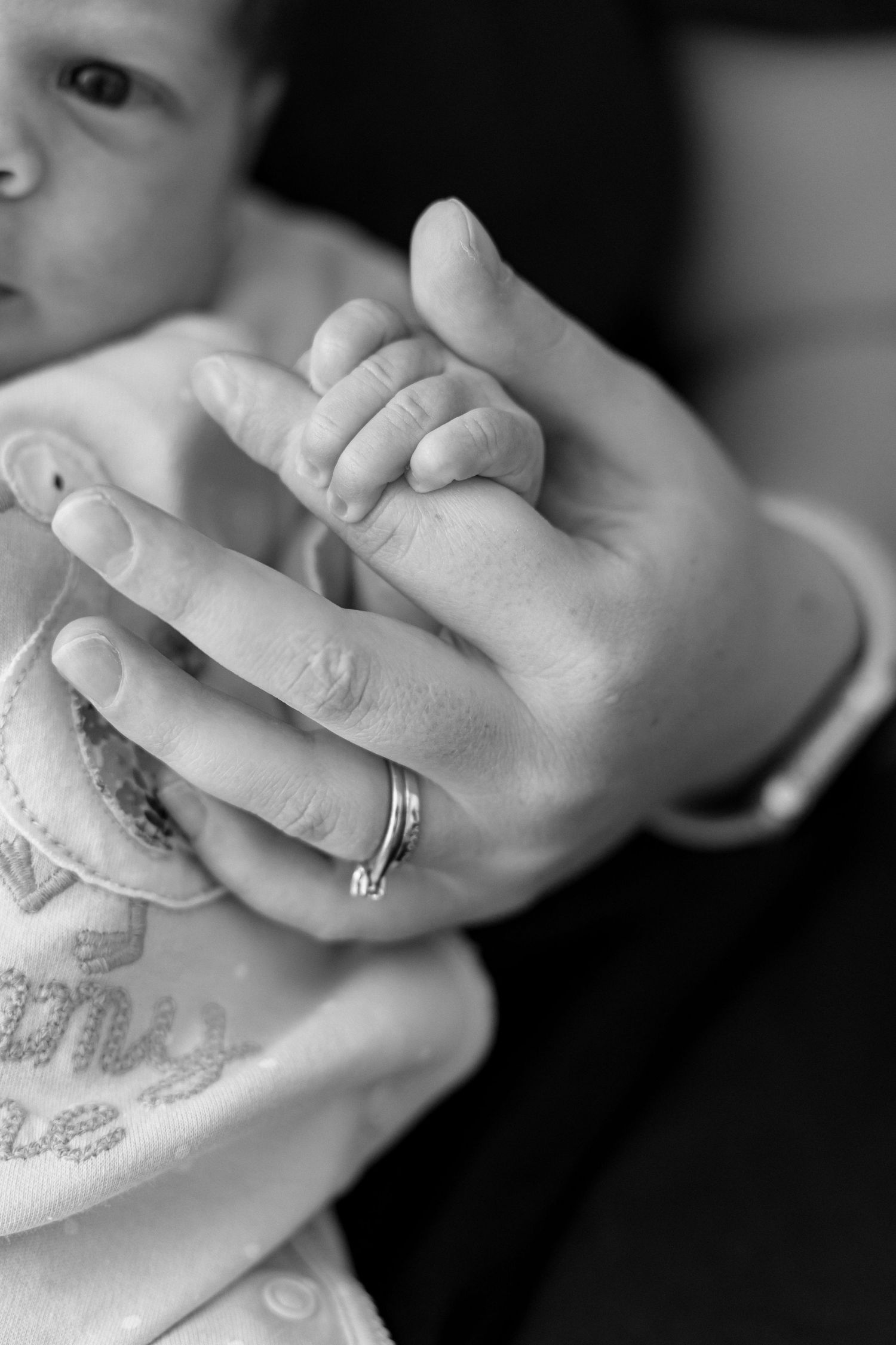 Close up of tiny baby feet being held by hands wearing wedding rings.