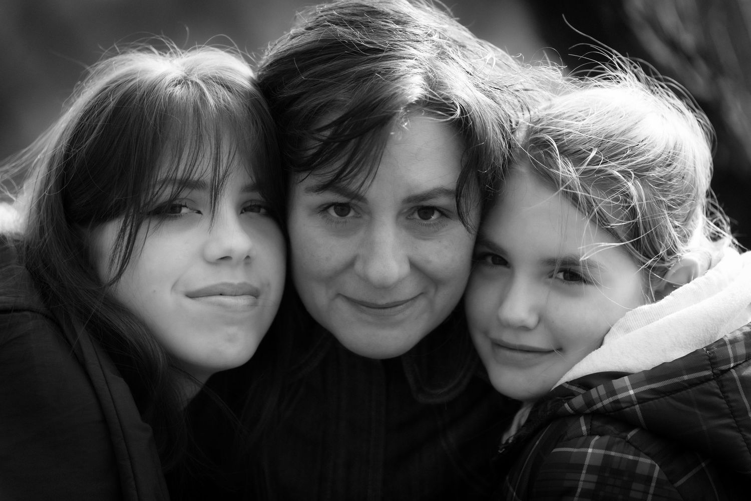 Black and white close-up portrait of three people in dark winter clothing.