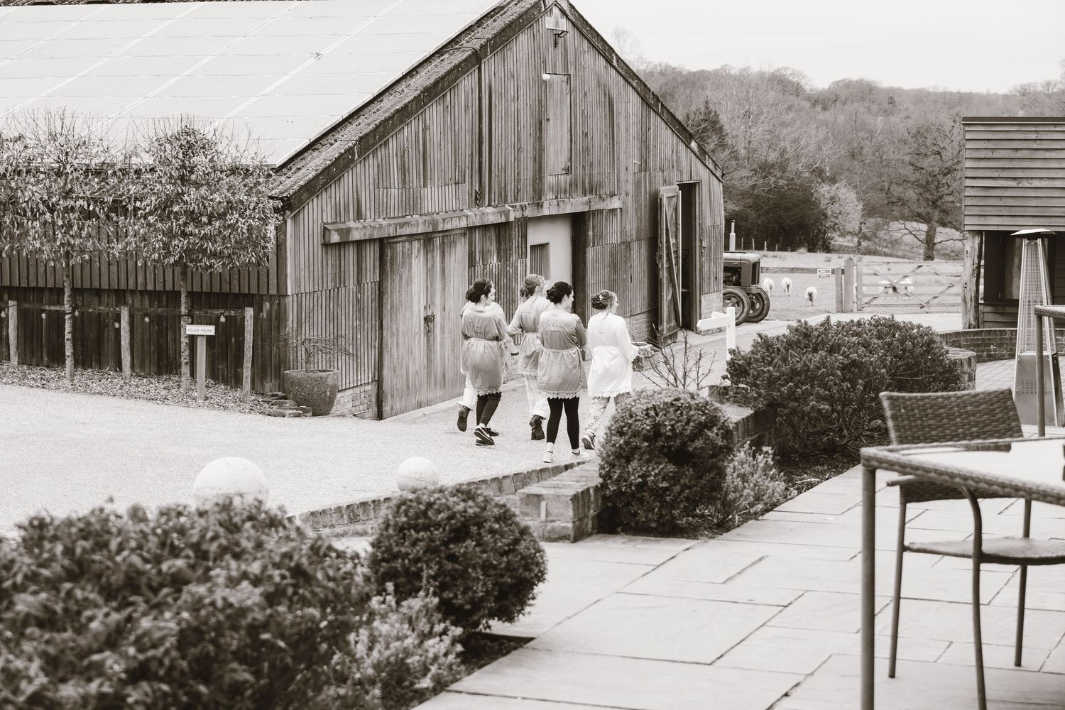Vintage photograph of a rustic wooden barn with people standing outside.