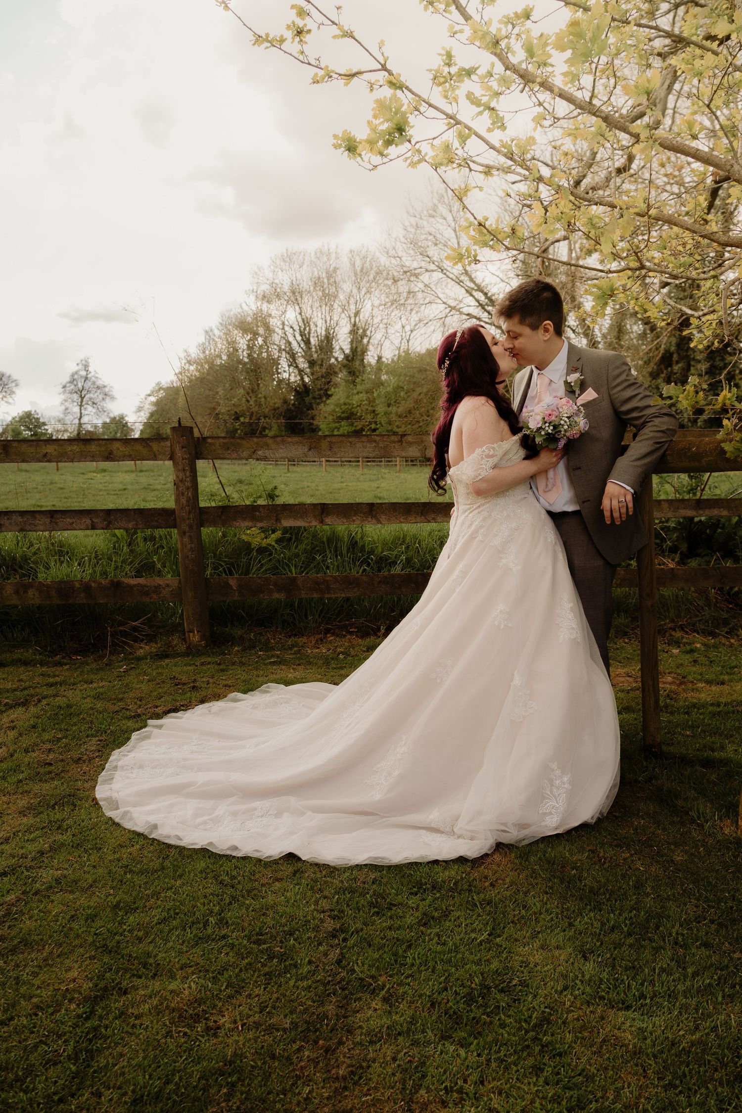 Newlyweds embrace under blooming spring trees in an outdoor garden setting.