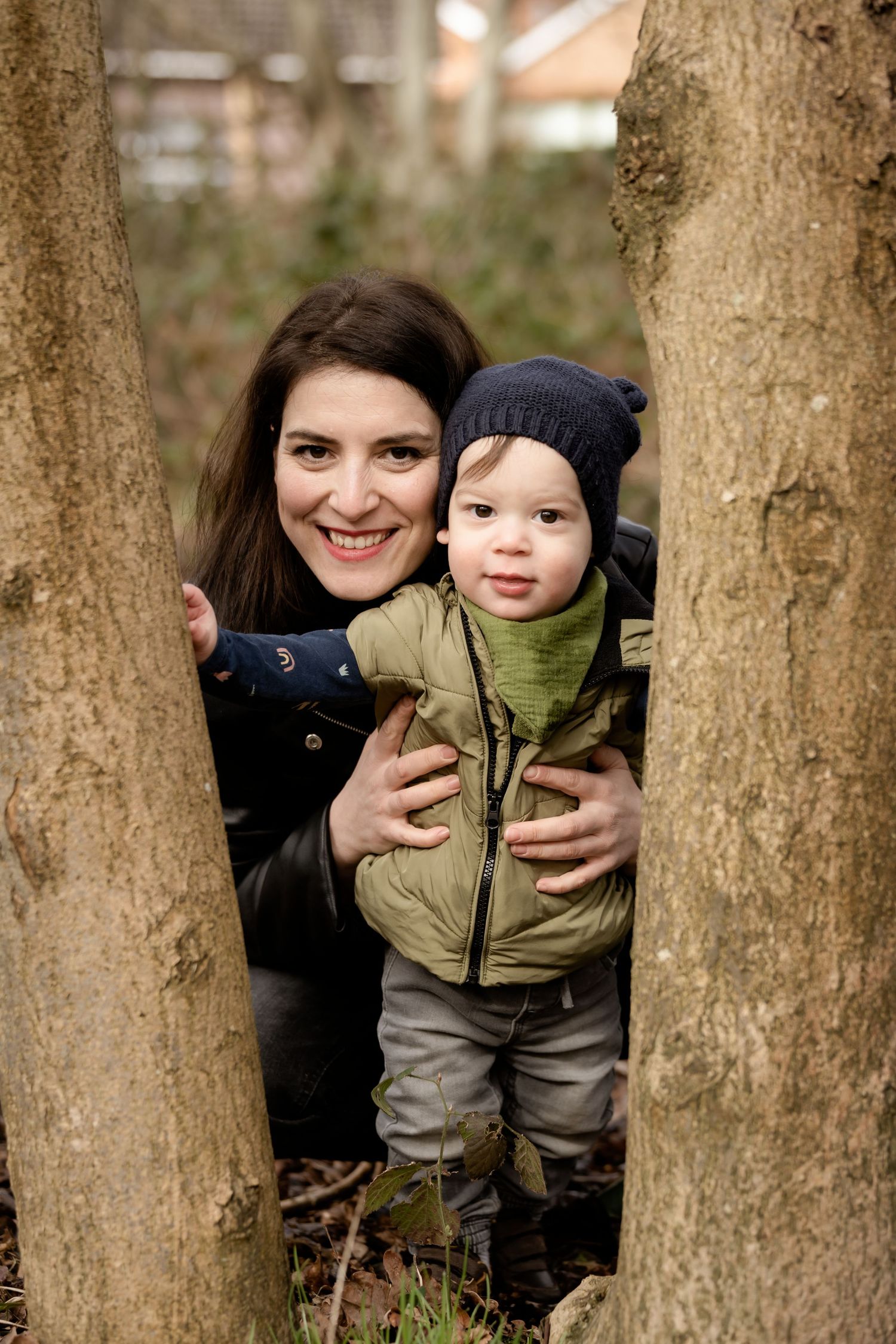 A playful peek between tree trunks in an outdoor nature setting during autumn.