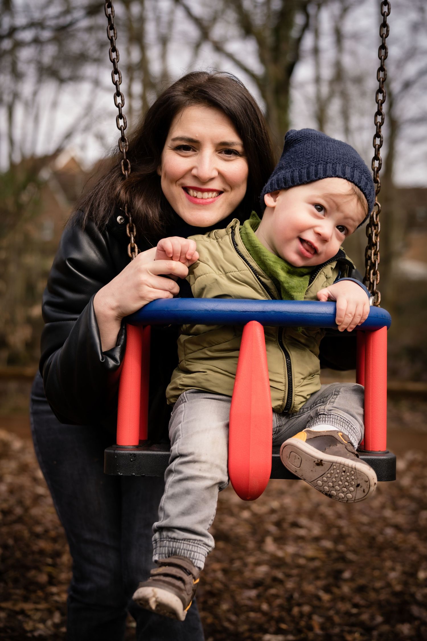 Joyful moments shared on a red playground swing in an autumn setting.