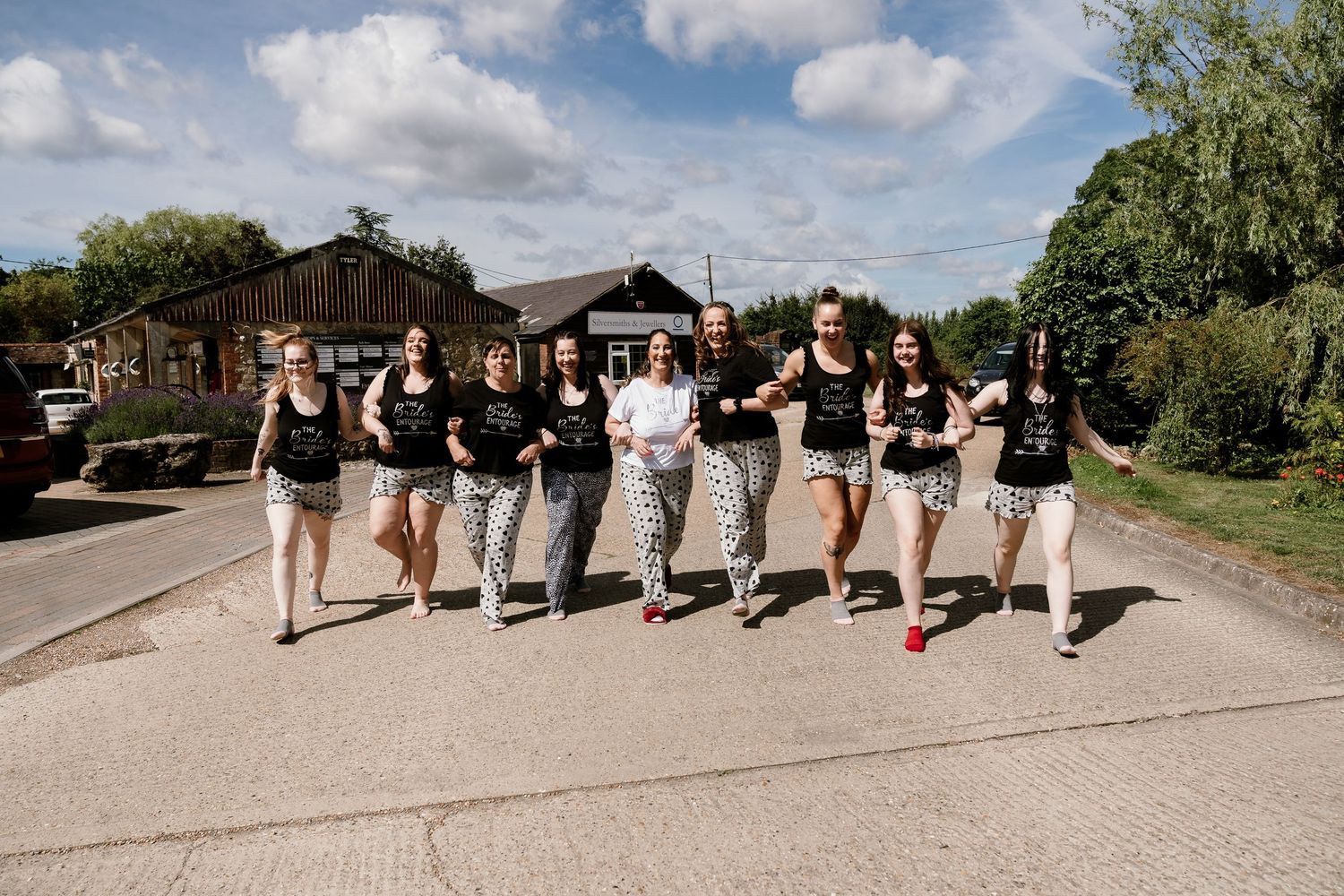 Wedding party posed outdoors on a grassy hill on a sunny summer day.