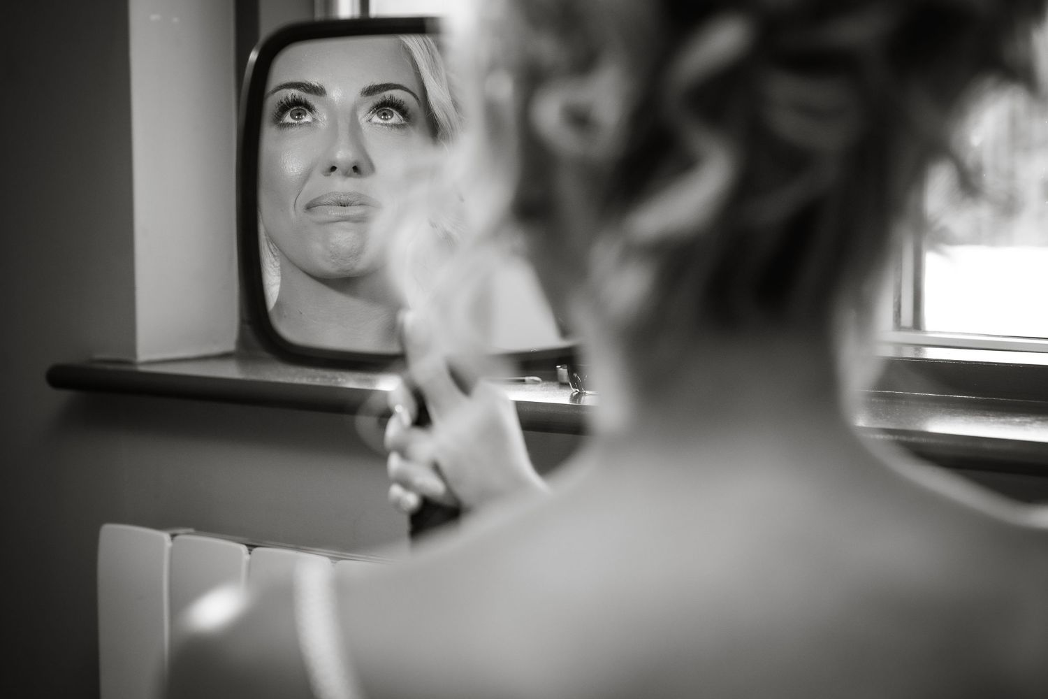Artistic black and white reflection of bridal preparations in a mirror.