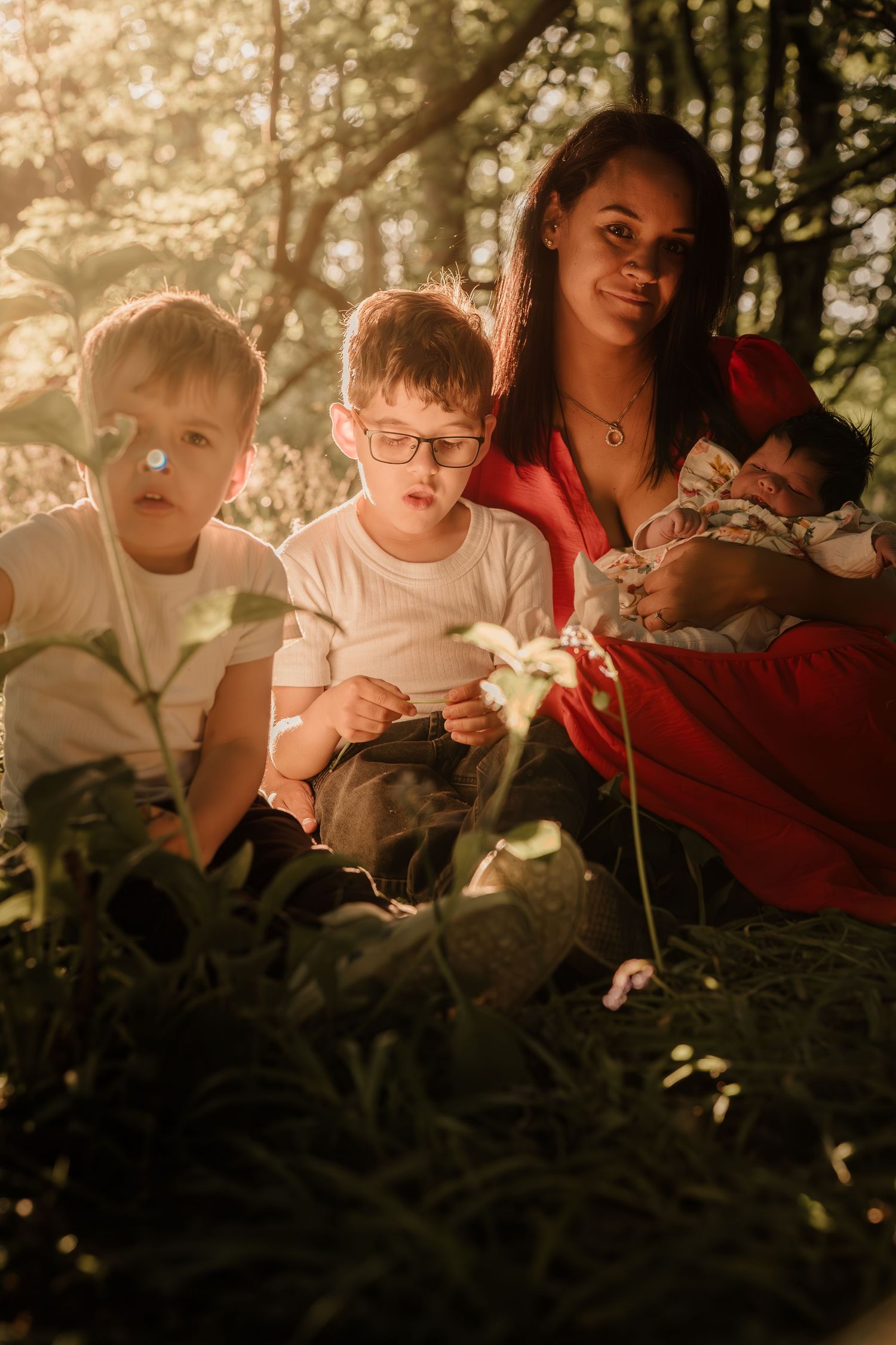 Family seated outdoors among trees during golden hour sunset.