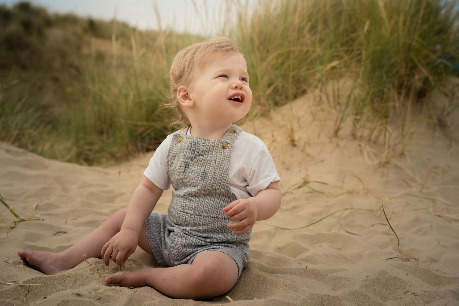 Joyful children playing in coastal sand dunes with beach grass.