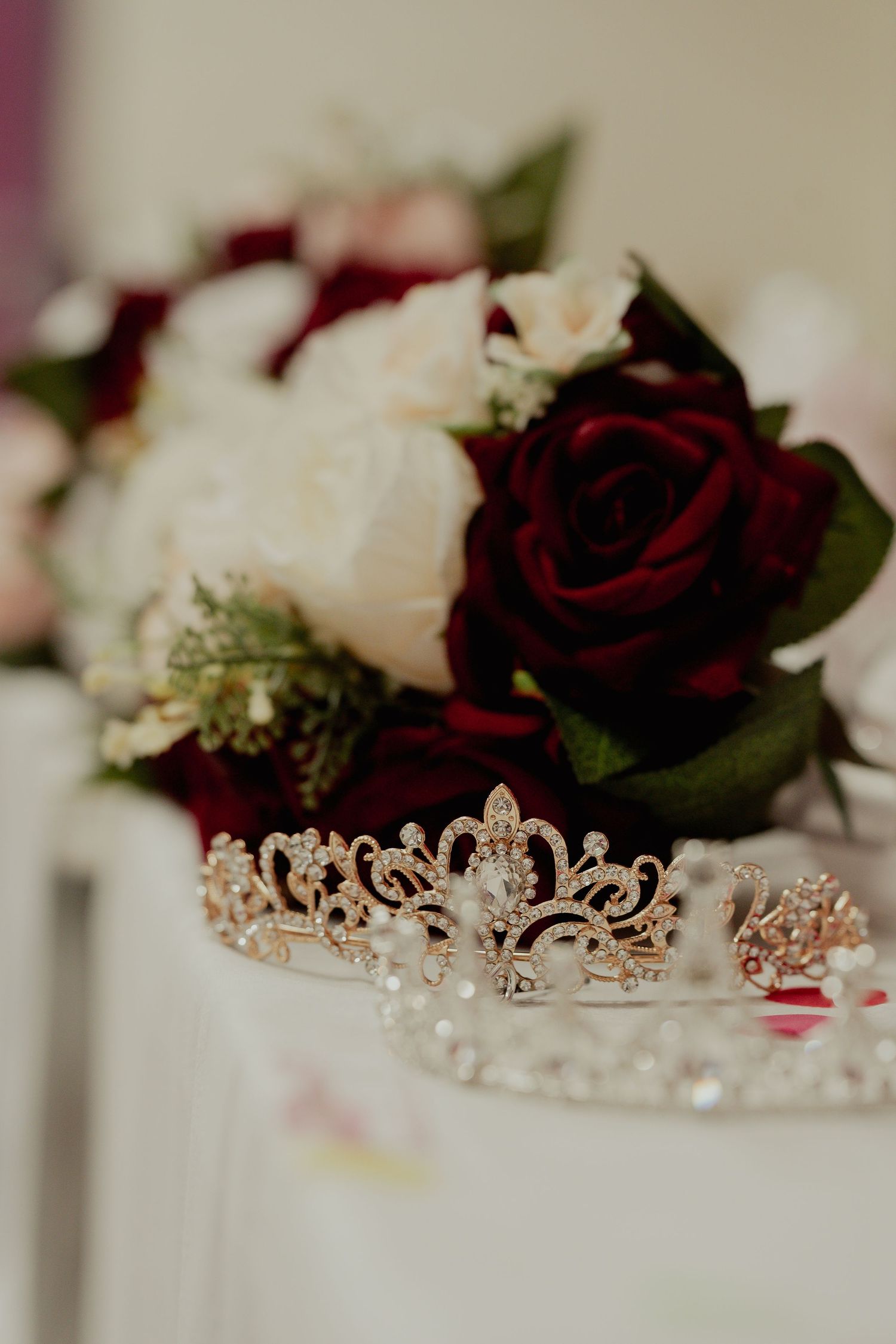 Elegant bridal tiara and bouquet with red and white roses displayed together.