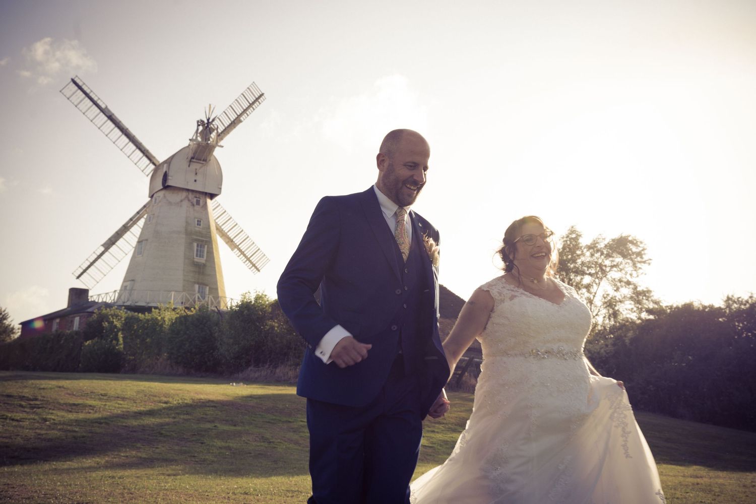 A couple poses in front of a traditional windmill during their wedding photoshoot.