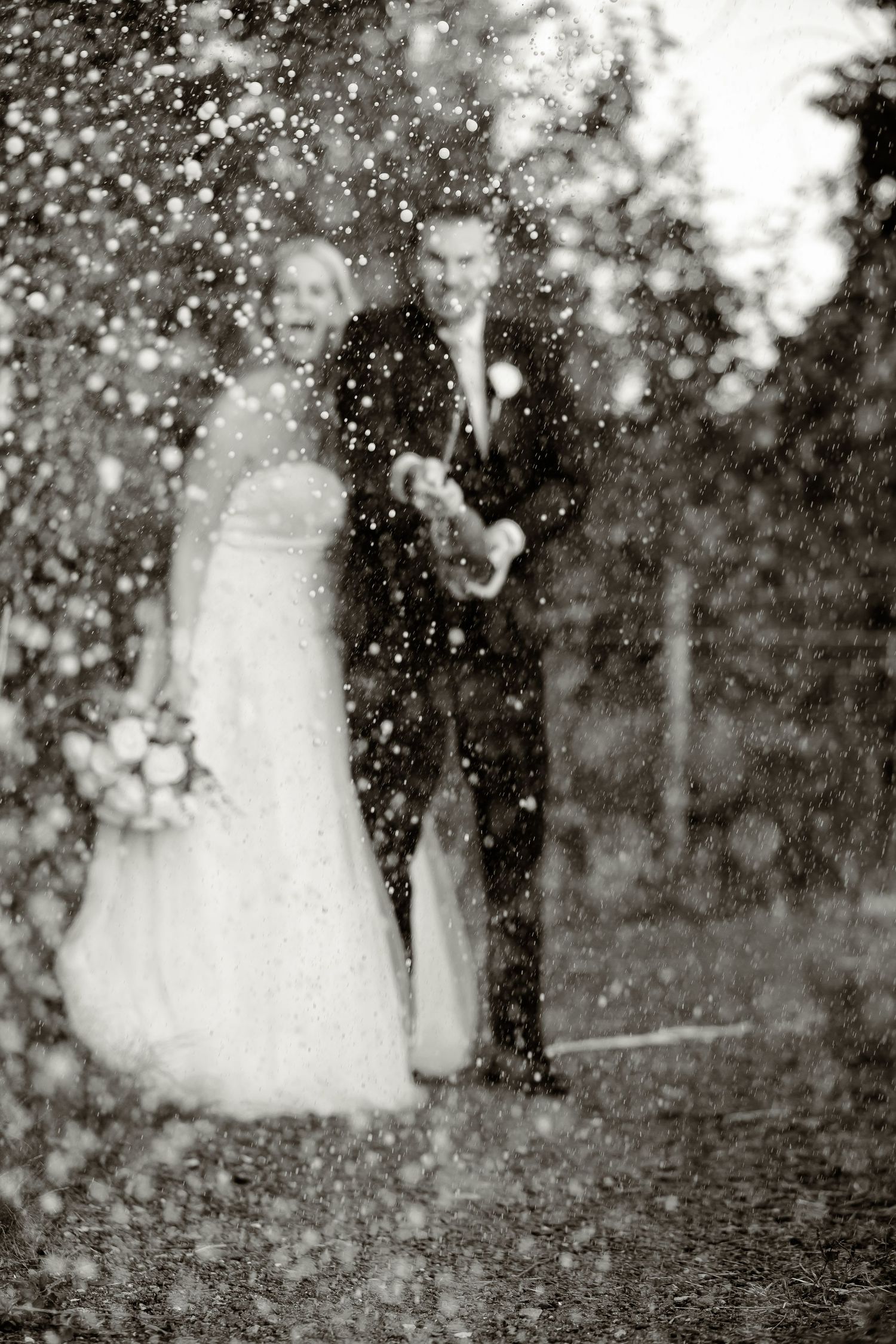 Black and white photo of newlyweds in a dreamy shower of sparkles and confetti outdoors.