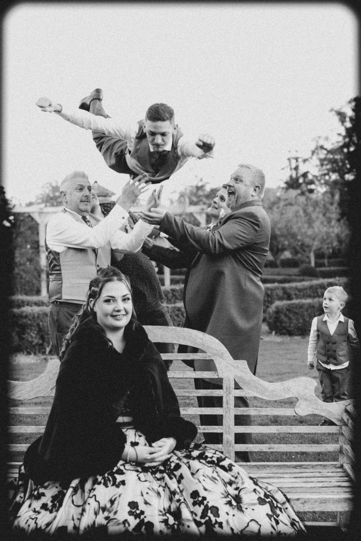 Playful black and white sequence of people jumping and posing on outdoor bench.